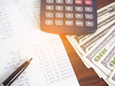 Kitap bankacılığı hesabına yakın kalem, masada dolar parası olan hesap makinesi.