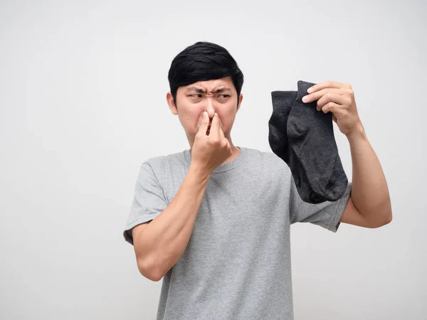 Asian man holding dirty socks close his nose feels smelly portrait