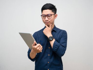 Gözlüklü genç adam tablet jestine bakıyor. İş konusunda düşünceli.