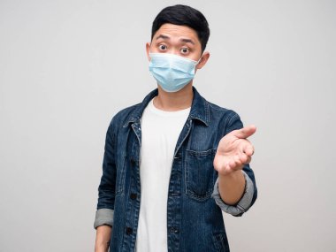 Tıbbi maske takan genç adam el sıkışmasını öneriyor.