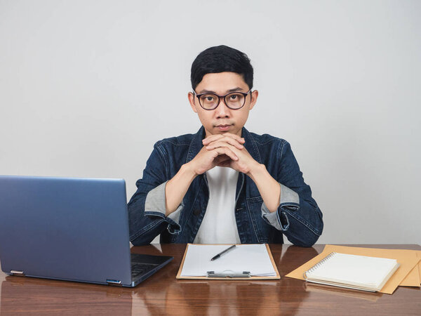 Asian businessman look confident sit at workplace table looking at you