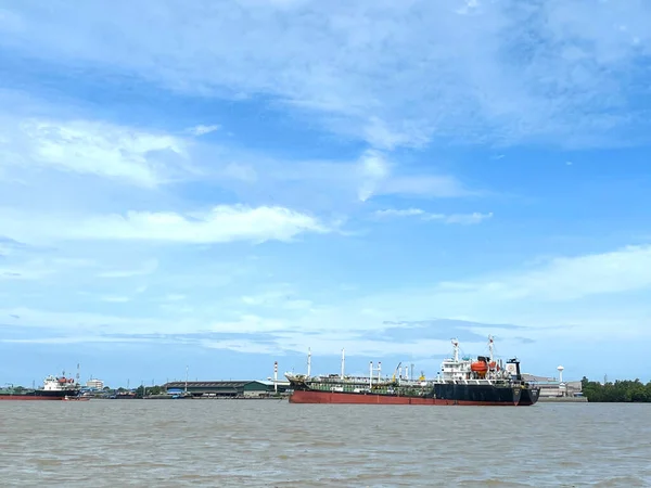 Cargo ship loading in the ocean background with the blue sky and white cloudy landscape,Logistic transportation concept