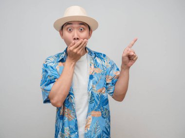 Young man wear hat beach shirt feels shocked close his mouth gesture point finger