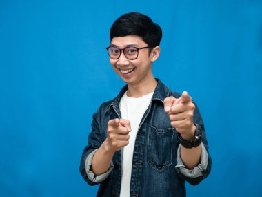 Positive man jeans shirt gesture point finger at you blue background