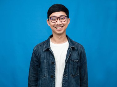 Young asian man jeans shirt gentle smile portrait blue background