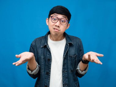 Young asina man jeans shirt confused blue background