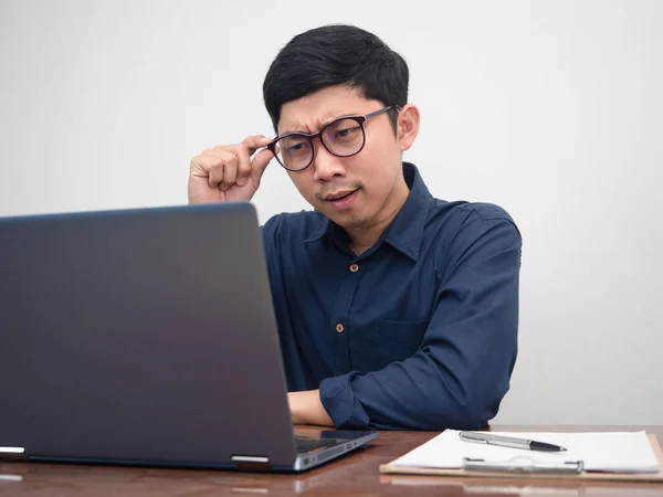 Asian man wear glasses looking at laptop on workplace table