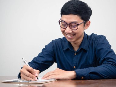 Asian businessman writing on document at the desk feels happy with his working