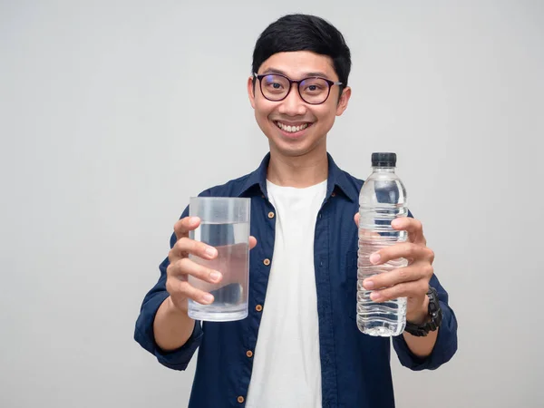 Positive asian man giving water bottle and a glass of water to you isolated