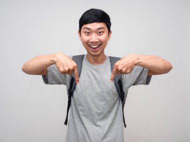 Positive man with school bag cheerful gesture point finger down