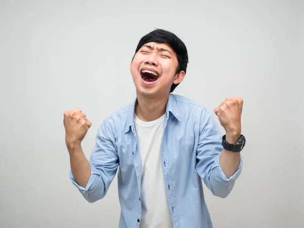 Neşeli genç adam, mutluluktan memnun. Yumruğunu göster.