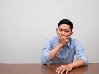 Üzüntülü Asyalı adam masada tek başına oturuyor.