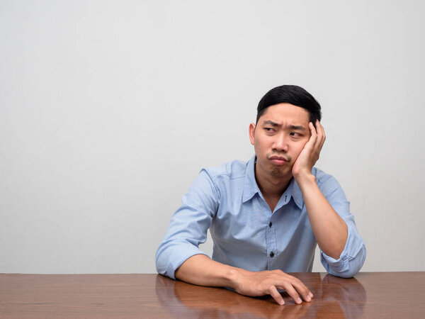 Asian businessman sit alone at table feels tried and disheartened