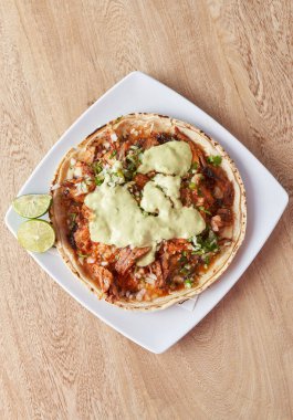 variety of delicious typical mexican food and ingredients such as salsas, red, green, guacamole, lemon, tomato and onion.