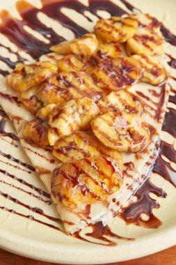 photo of a delicious crepe with banana and decorated with liquid chocolate. sweet crepe.