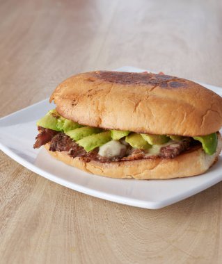 picture of delicious sandwich or Torta with meat, avocado and cheese on wooden table.. typical mexican food.
