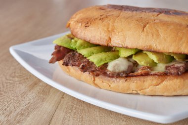 picture of delicious sandwich or Torta with meat, avocado and cheese on wooden table.. typical mexican food.
