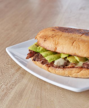 picture of delicious sandwich or Torta with meat, avocado and cheese on wooden table.. typical mexican food.