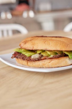 picture of delicious sandwich or Torta with meat, avocado and cheese on wooden table.. typical mexican food.
