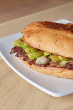 picture of delicious sandwich or Torta with meat, avocado and cheese on wooden table.. typical mexican food.