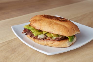 picture of delicious sandwich or Torta with meat, avocado and cheese on wooden table.. typical mexican food.