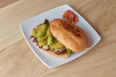 picture of delicious sandwich or Torta with meat, avocado and cheese on wooden table.. typical mexican food.