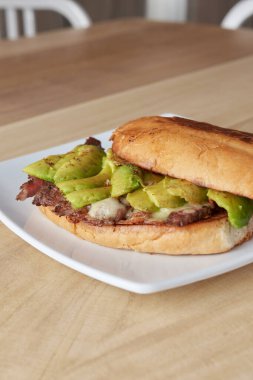 picture of delicious sandwich or Torta with meat, avocado and cheese on wooden table.. typical mexican food.