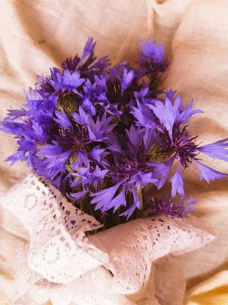 夕日のテーブルの上に白いヴィンテージリボンの紫色の花の花束 — ストック写真