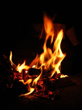 Parlak sarı bir alev yakar şenlik ateşinde, gece odunların arasında