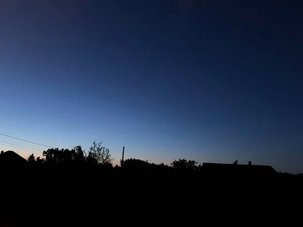 Wunderschöner Blauer Sonnenuntergang Über Den Schwarzen Silhouetten Von Bäumen Und — Stockfoto