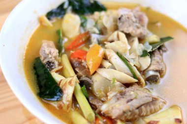 Baharatlı domuz kemiği ve saman mantarı, yabani domates, ahşap masadaki beyaz kasede Tom yum çorbası. Tom Yum Tayland usulü domuz çorbası..
