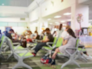 Chiang Rai uluslararası havaalanındaki kahve dükkanının yanında bekleyen insanların ya da yolcuların bulanık görüntüleri. Bagajı olan gezgin koltukta oturuyor ve uzun kuyruk halindeki bokeh ışığıyla dolu.