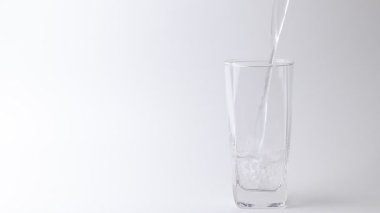 Tatlı su içeceğini gri arka plandaki bardağa döküyorum. Dökülen su