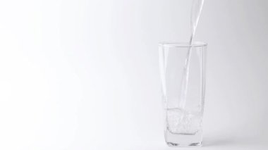 Tatlı su içeceğini gri arka plandaki bardağa döküyorum. Dökülen su