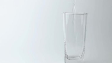 Tatlı su içeceğini gri arka plandaki bardağa döküyorum. Dökülen su