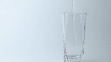 Tatlı su içeceğini gri arka plandaki bardağa döküyorum. Dökülen su