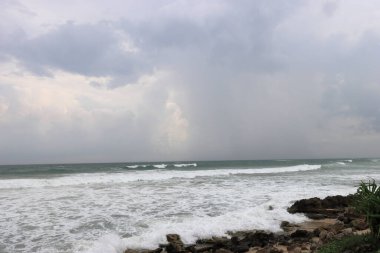 Sahilde güzel beyaz su kabarcıkları. Dalgaların dalgalandığı bir sahil. Kayalıkların oluşturduğu deniz dalgaları ve kabarcıklar.