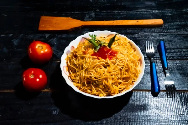 Asian noodles with vegetable, sauce and peppers. Isolated on wooden background
