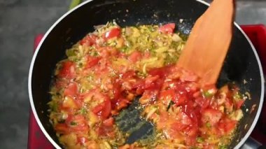  Onion, Tomato, chilli and sauce in hot oil on pen. Slow motion video