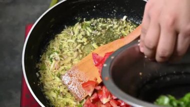 Tomato, chilli. onion cooking in pen on hot oil.