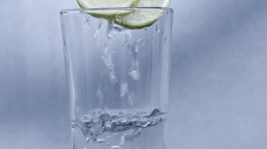 Su limonlu bir bardağa dökülüyor.