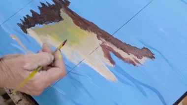 Sanatçı bir resim çizer. Boyalar ve fırçalar.