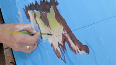 Sanatçı bir resim çizer. Boyalar ve fırçalar.
