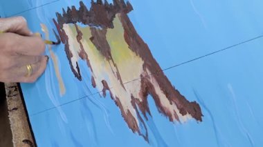 Sanatçı bir resim çizer. Boyalar ve fırçalar.