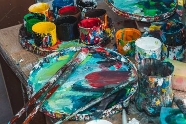 Ressam resimlerini parlak renklerle çizer.