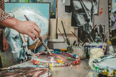 Ressam resim yapar. Fırçalar, tablolar