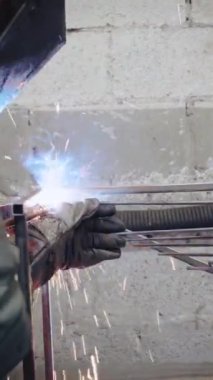 Dikey video, fabrika işçisi metali kesiyor. Kıvılcımlar. Üretim