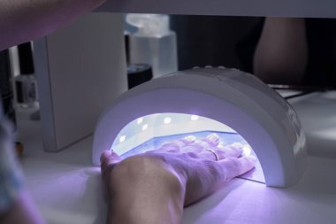 Manikür işlemi, el lambanın altında.