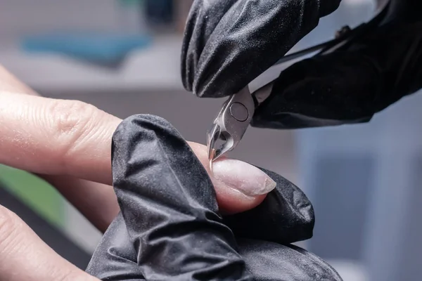 The process of manicure in a beauty salon close-up. Cuticle removal
