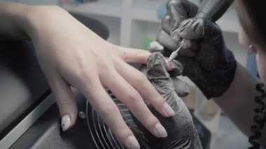 The process of manicure in a beauty salon close-up. Removal of the coating by the device
